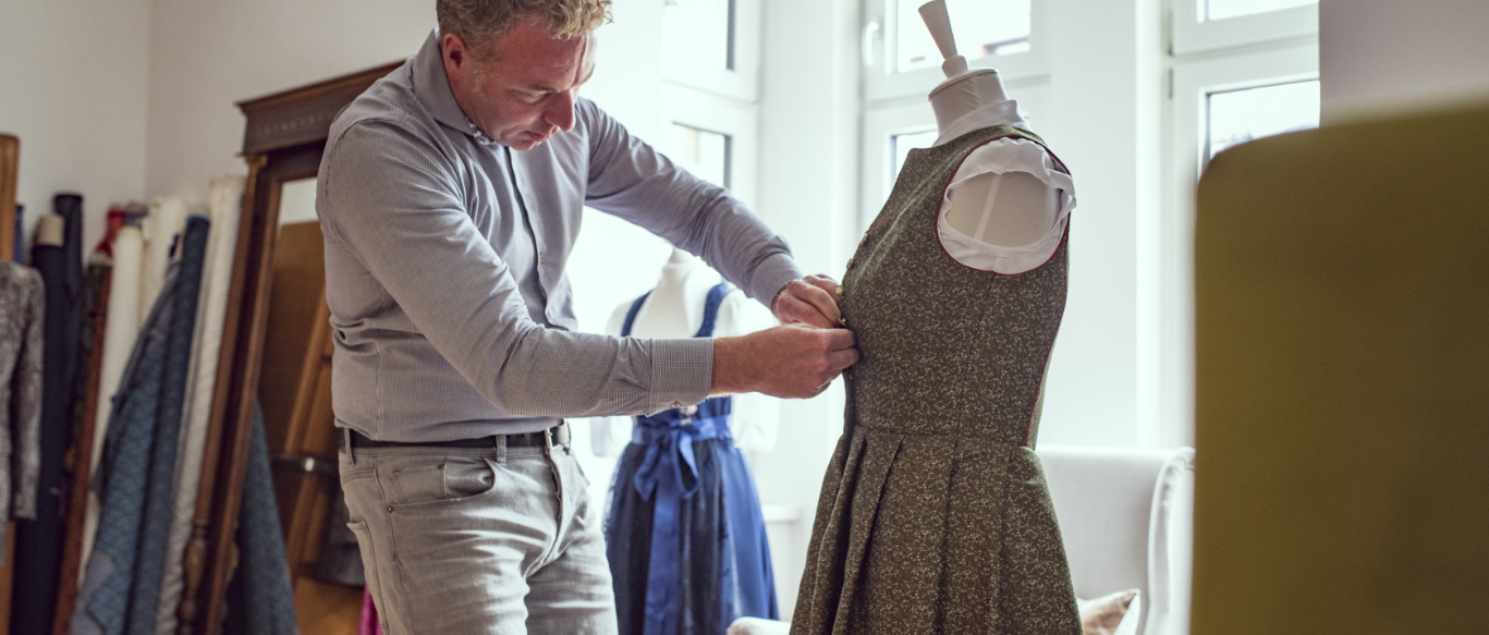 Kleidermacher beim Zuknöpfen eines Dirndls.